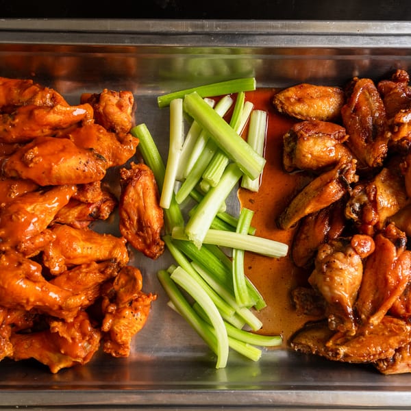 Buffalo and BBQ wings with celery on a tray