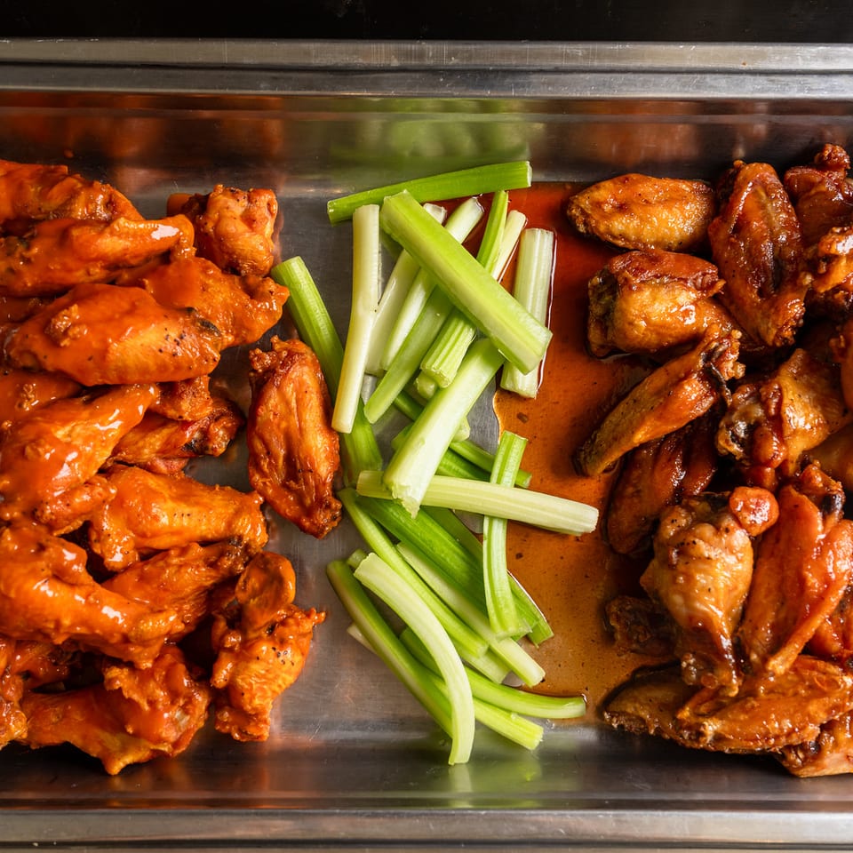 Buffalo and BBQ wings with celery on a tray