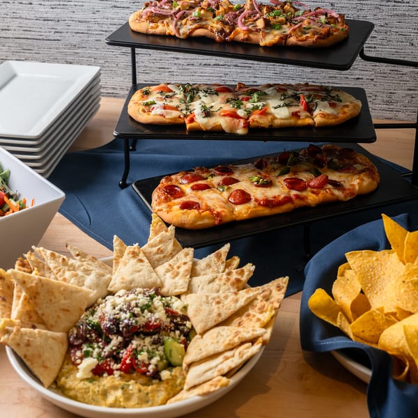 Flatbread trio on a tiered stand with a garden salad, hummus with pita, and tortilla chips.