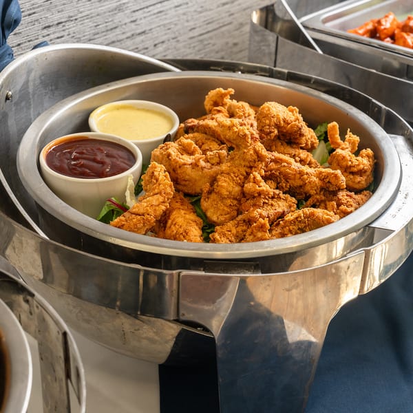 Fried chicken tenders with dipping sauces in a chafing dish