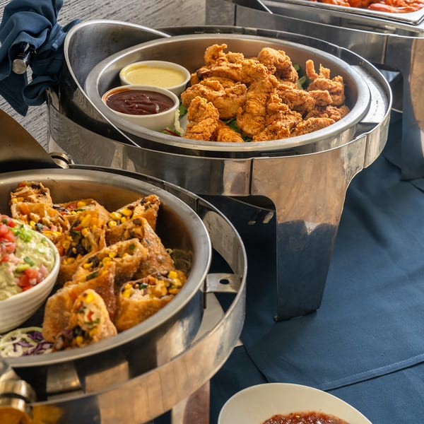 Chafing dish buffet with chicken tenders, egg rolls, and wings